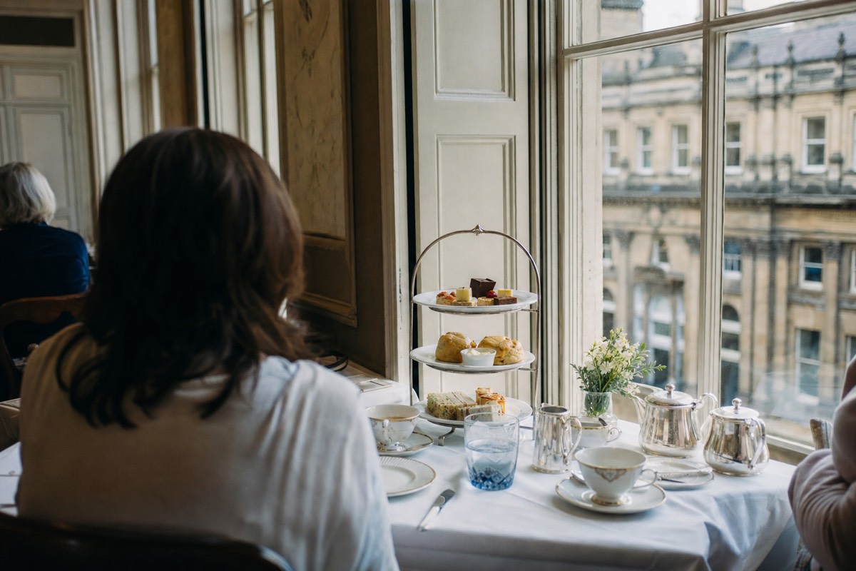 An afternoon tea table laid with a tiered stand, scones and a teapot