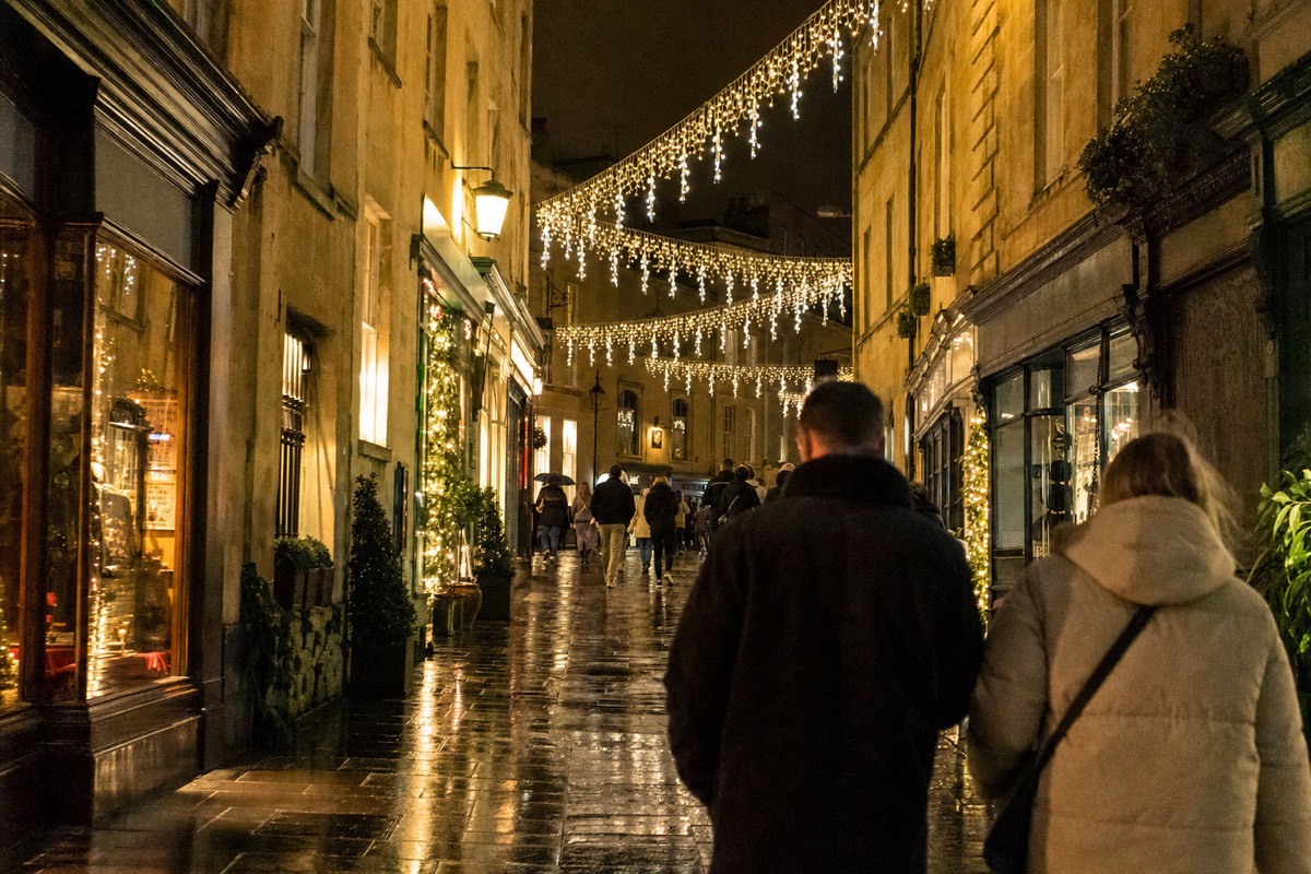 Festive lights strung above a shopping street at dusk