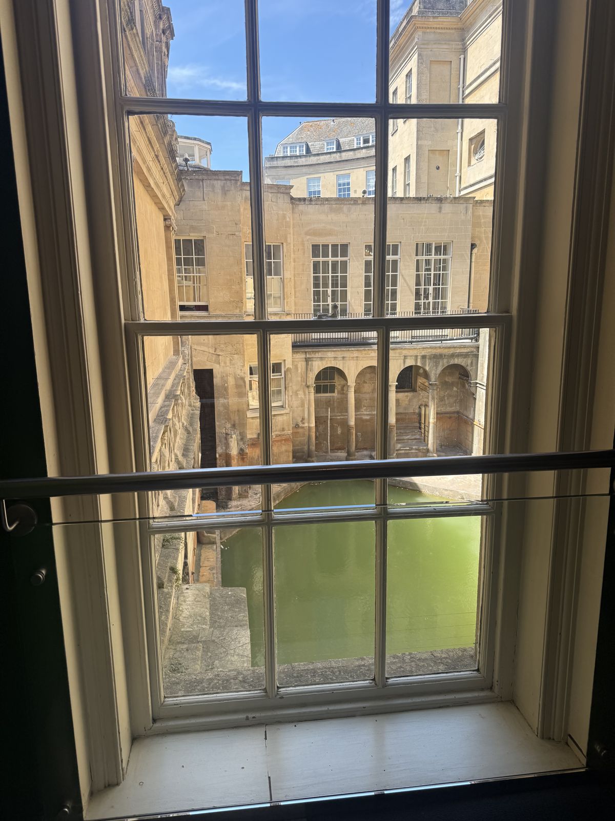The Great Bath at the Roman Baths seen through a Georgian sash window